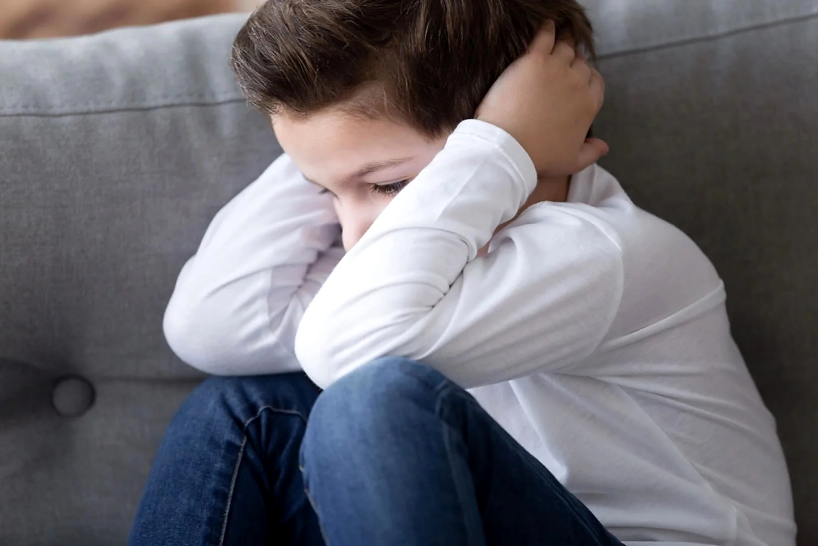 Young child distressed and withdrawn on a sofa — Youth Mental Health First Aid
